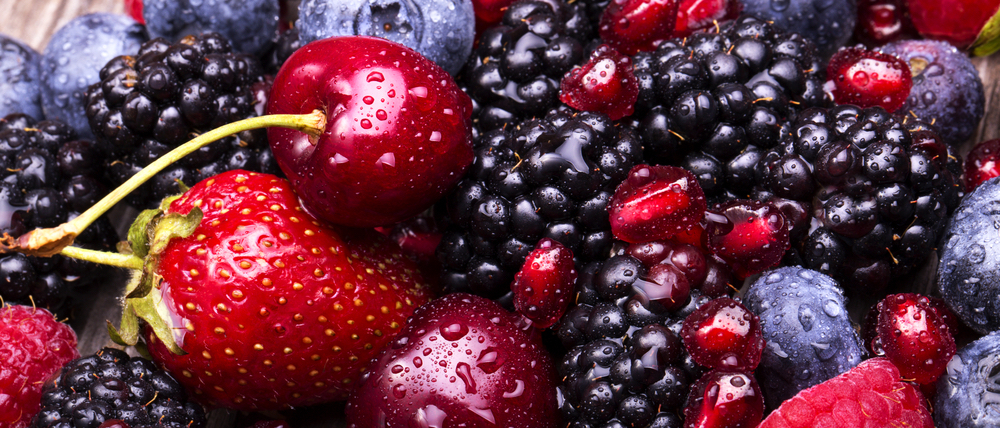 tasty summer fruits on a wooden table. Cherry, Blue berries, strawberry, raspberries, Blackberries, pomegranate